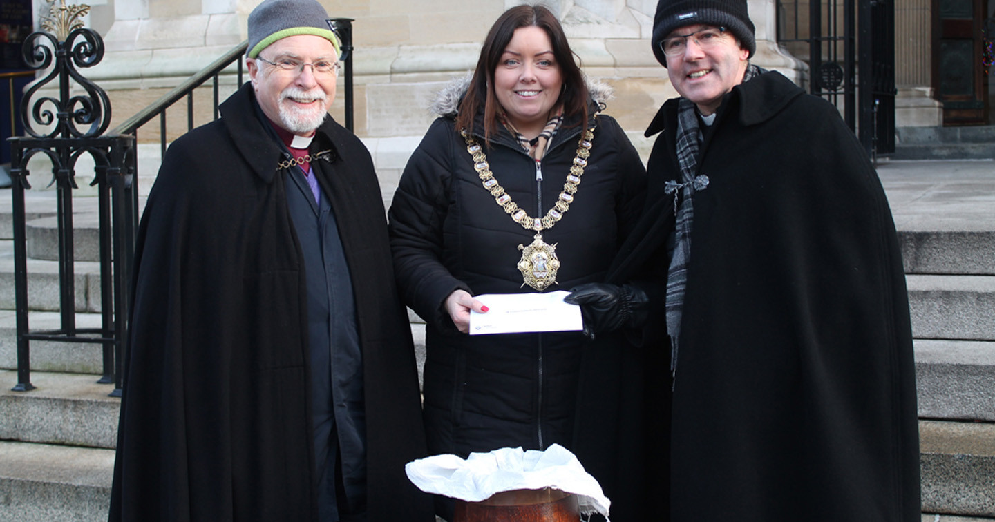 Lord Mayor of Belfast Councillor Deirdre Hargey makes a donation to Black Santa. With her are the Bishop of Down and Dromore, the Rt Rev Harold Miller, left, and the Dean of Belfast, the Very Rev Stephen Forde.