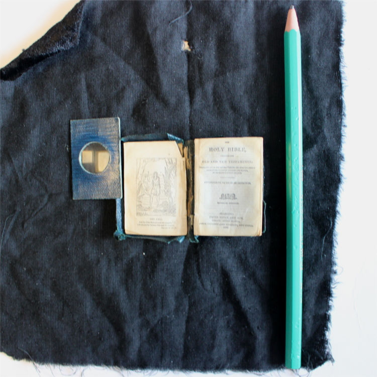 Eleanor Knott's miniature Bible, complete with magnifying glass and a pencil for scale.