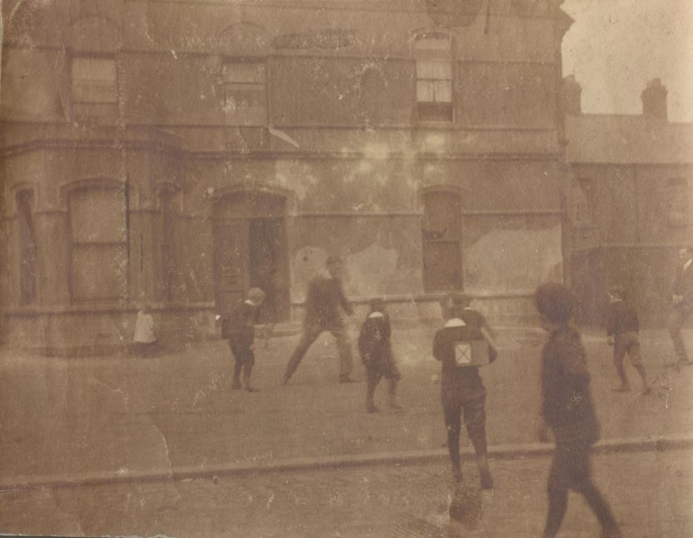 Image labelled ‘H.G. Studdart Kennedy', which appears to show him kicking football with young people in front of the Mission building, RCB Library MS 295