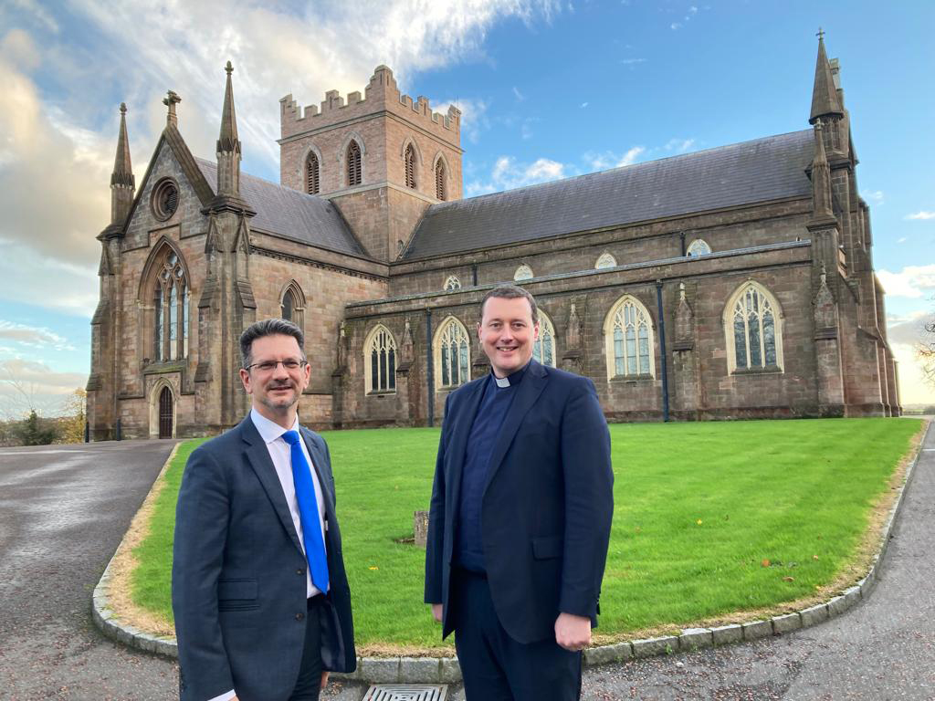 Minister of State Steve Baker MP and the Dean of Armagh, the Very Revd Shane Forster, with St Patrick's Church of Ireland Cathedral in the background.