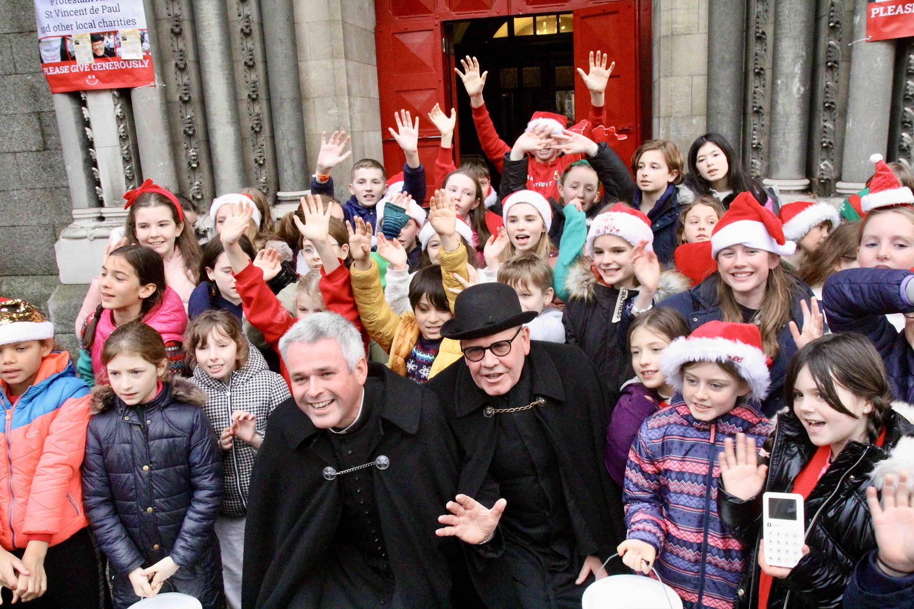 Canon Paul Arbuthnot and Fred Deane with the choir of Kildare Place School at the launch of the Black Santa Sit Out at St Ann's, Dawson Street.