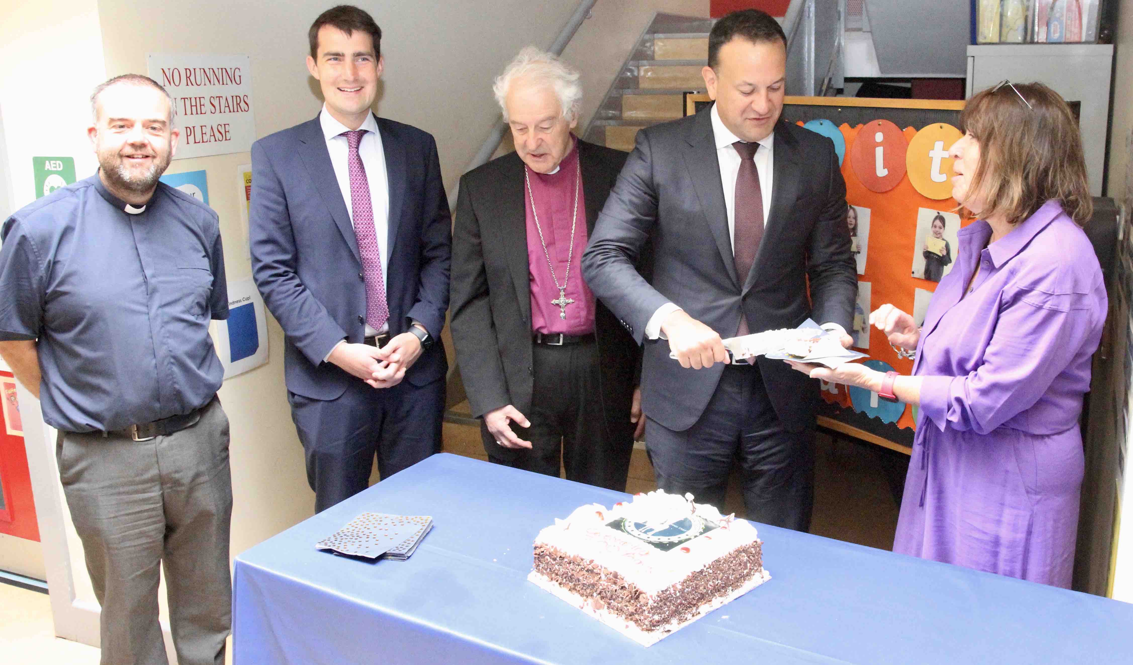 The Taoiseach cuts the cake for the Revd Colin McConaghie, Minister Jack Chambers, Archbishop Michael Jackson and principal Sandra Moloney.