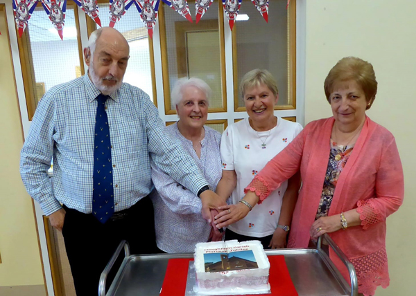 Cutting the anniversary cake are children of founder members of the Church of the Ascension, Cloughfern Parish: Tom Fulton, Maebeth (Waite) Wilson, Christine Hunter, and Eleanor (Fulton) Robinson.